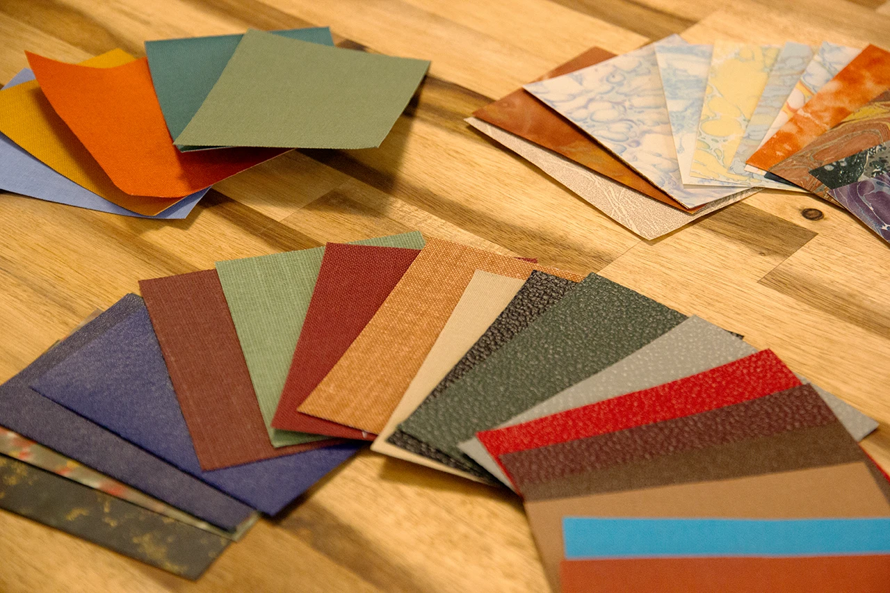 Échantillons de papiers de création et de toiles de reliure haut de gamme présent chez l'atelier Forme contre forme.