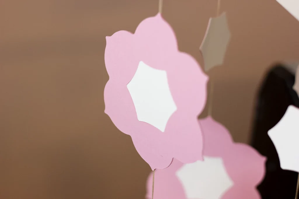 Fleur de narcisse réalisée en marqueterie papier rose et blanc pour un mobile d’enfant à l’atelier Forme contre forme.