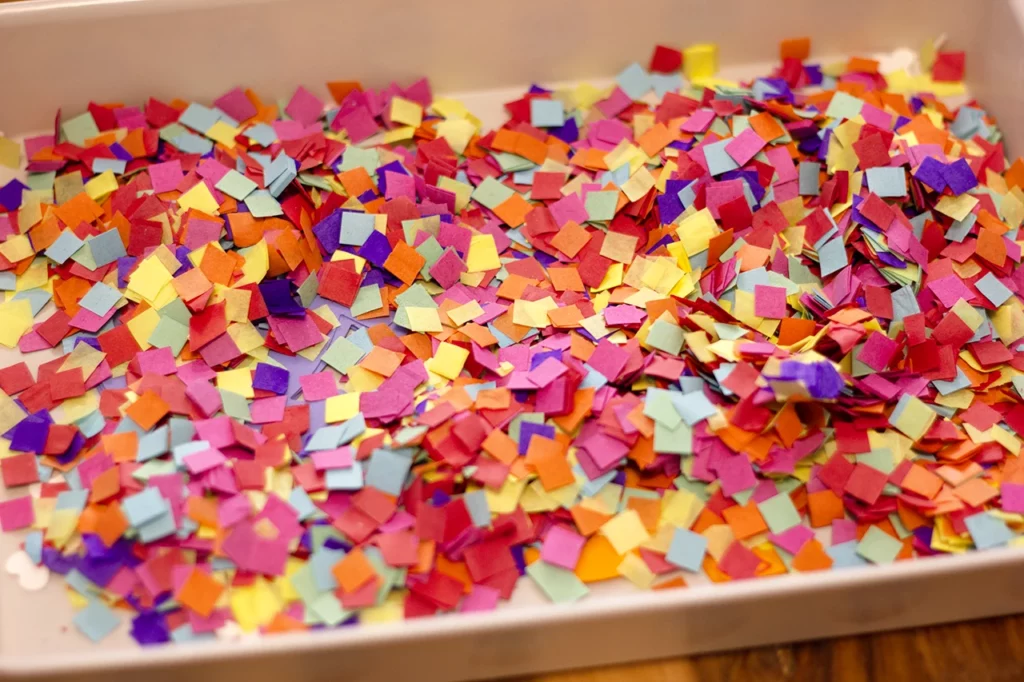 Bac contenant les formes réalisées pour un anniversaire sur la thématique « dinosaure », recouvert de confettis.