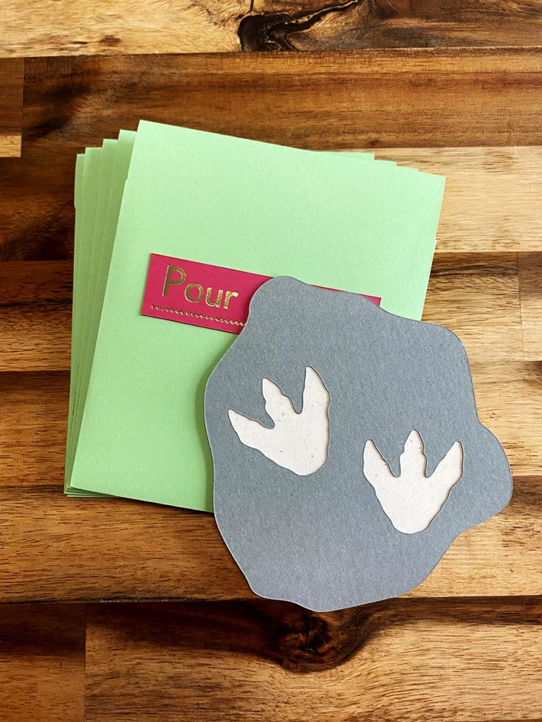 Enveloppe verte d'eau personnalisée, vue de face, avec une étiquette réalisée en dorure à chaud pour indiquer le prénom de l’enfant à qui l’invitation est destinée.