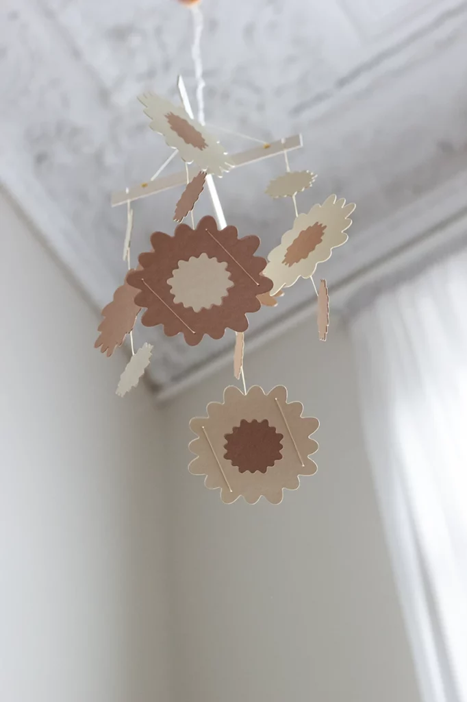 Mobile bébé en marqueterie de papier personnalisable, couleur vanille et coco, vue de dessous avec une fleur de chrysanthème.