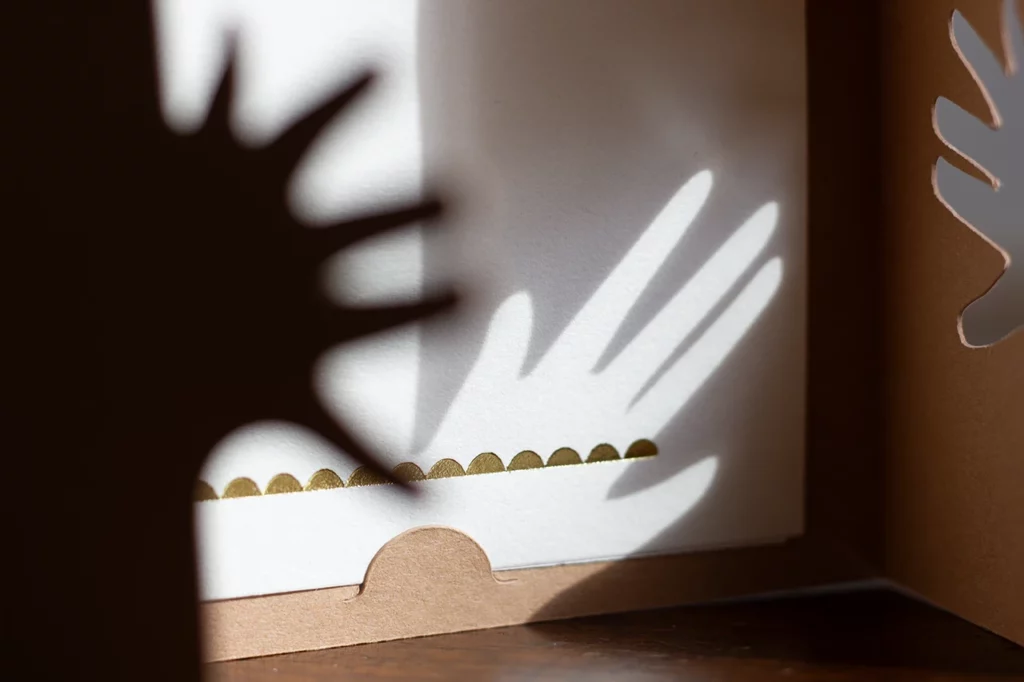 Photo du bas du livret de cartes empreintes pour bébé personnalisable ouvert, avec un effet d'ombrage de la main, couleur cocos, et des ornements faits à la dorure à chaud. Photo du bas du livret de cartes empreintes pour bébé personnalisable ouvert, avec un effet d'ombrage de la main, couleur cocos, et des ornements faits à la dorure à chaud.