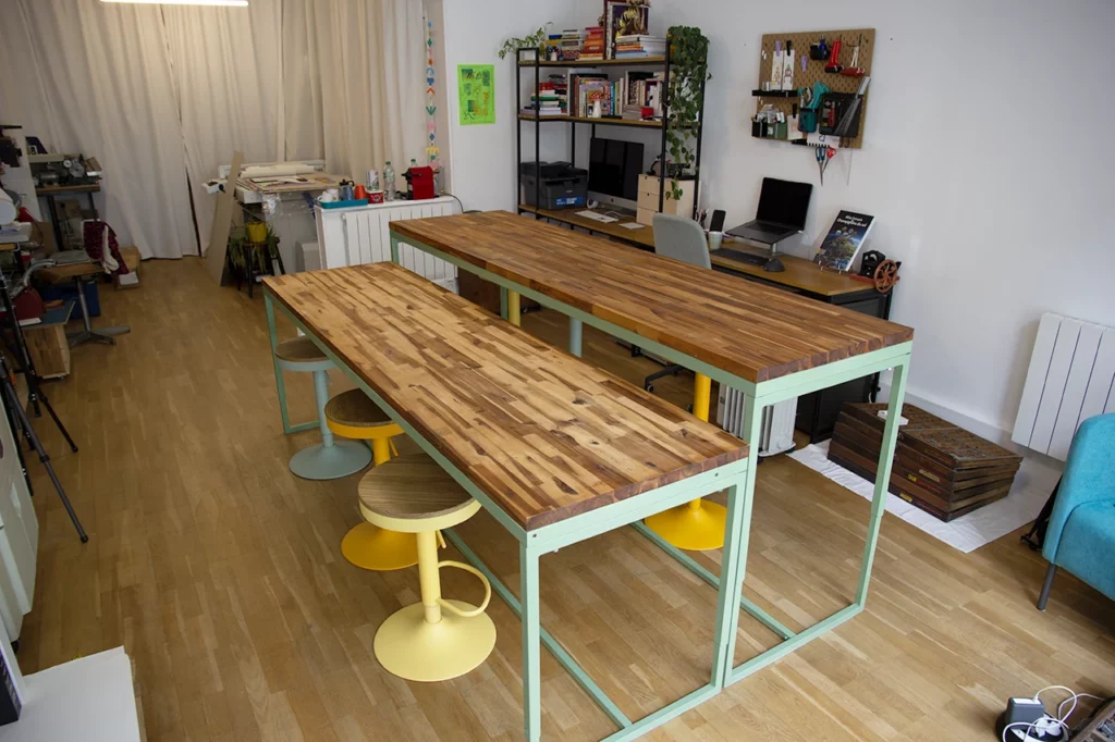 Table sur-mesure en bois et métal, vert olive, avec deux plateaux modulables en acacia, en position intermédiaire pour travailler assis.