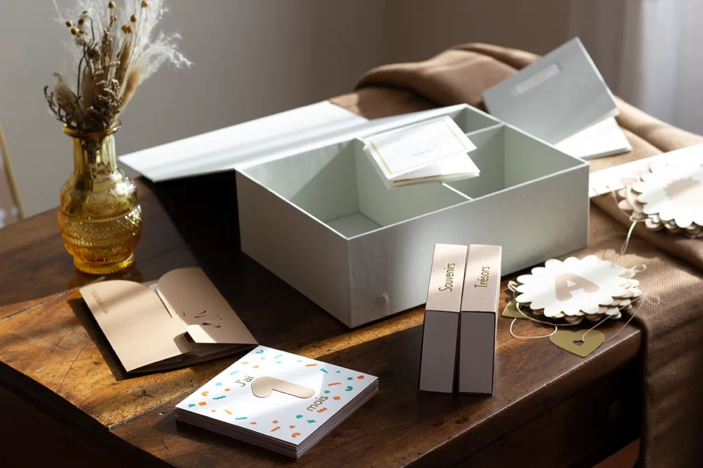 Vue d'ensemble du coffret de naissance personnalisé en toile grise claire avec du papier blanc et cocos, issu de la collection Tendresse 2024-2025.