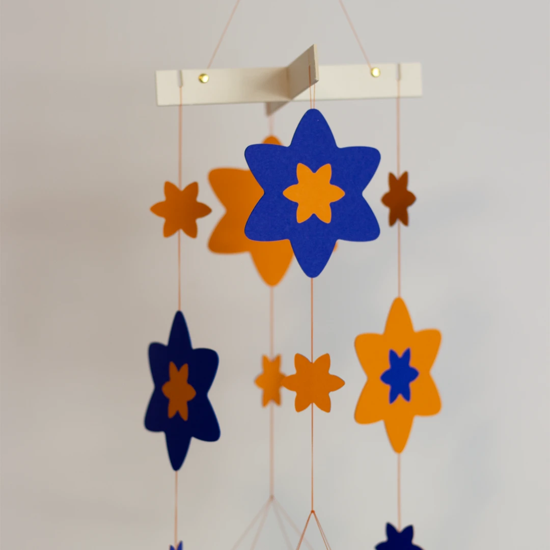 Zoom sur les fleurs de jonquille du mobile bébé en marqueterie de papier personnalisable, couleurs bleu outre-mer et jaune dahlias 1
