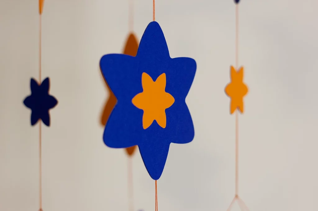 Zoom sur les fleurs de jonquille du mobile bébé en marqueterie de papier personnalisable, couleurs bleu outre-mer et jaune dahlias.