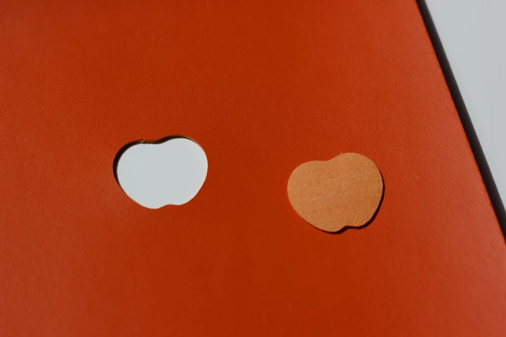 Forme évidée et silhouette pleine d'une pomme, découpées dans du cuir de pomme orange (SIDRA), fourni par Schmedt.