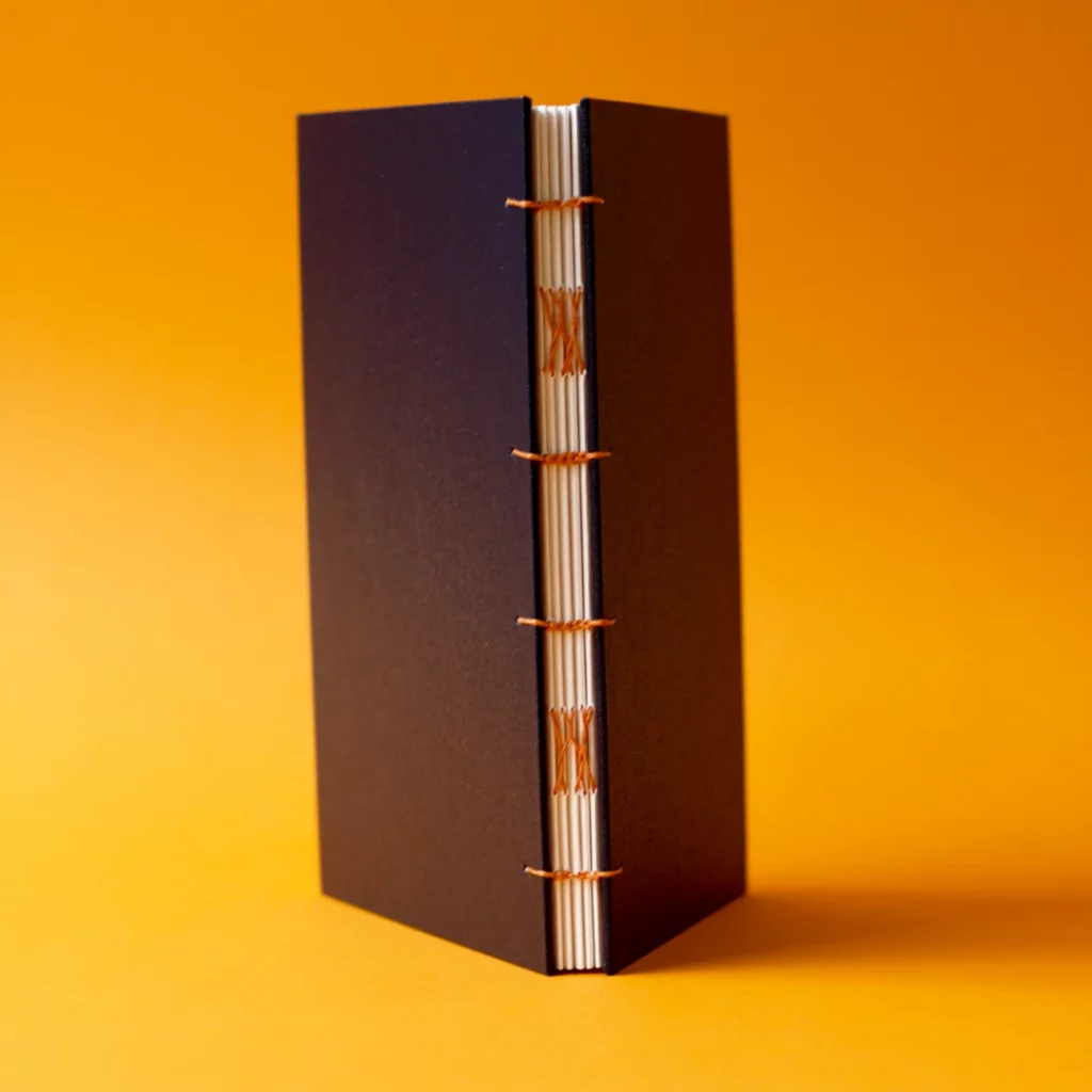 Carnet avec reliure copte, couverture similicuir noir et fil de lin abricot, papier Fedrigoni — position verticale — Atelier Forme contre forme, Bordeaux.