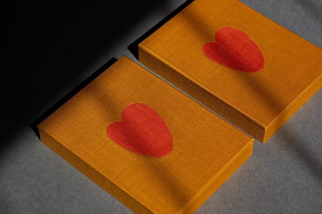 Boîtes à rabat aimanté en toile du Marais jaune moutarde, ornées d’une marqueterie de toile orange en forme de cœur — Atelier Forme contre forme, Bordeaux.